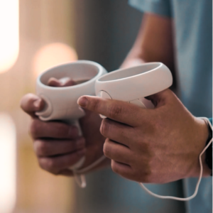 A person holding the hand devices which are used to move around in their virtual kitchen.